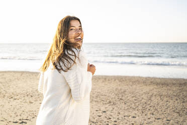 Cheerful beautiful woman spending leisure time at beach during sunny day - UUF22345