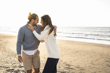 Glückliches junges Paar umarmt am Strand während eines sonnigen Tages - UUF22354