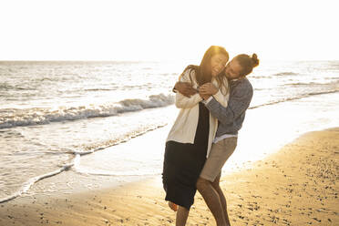 Cheerful couple enjoying at beach during sunny day - UUF22355