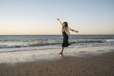 Sorglose Frau läuft am Strand gegen den klaren Himmel bei Sonnenuntergang - UUF22359