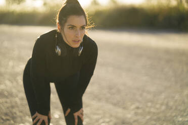 Tired young woman looking away while standing on land during sunset - MPPF01353