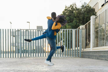 Junger Freund hebt Freundin beim Tanzen auf der Straße hoch - MPPF01412