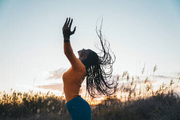 Teenage girl with eyes closed tossing hair in filed during sunset - MPPF01416