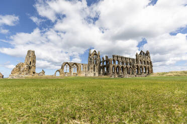 Whitby Abbey auf Graslandschaft gegen bewölkten Himmel an einem sonnigen Tag, Yorkshire, UK - WPEF03856