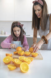 Mutter und Tochter schneiden Orangen in der Küche - SNF00898