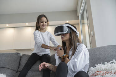 Smiling daughter looking at mother using virtual reality at home - SNF00910