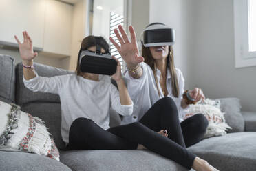 Tochter und Mutter machen eine Stop-Geste bei der Nutzung der virtuellen Realität im Wohnzimmer - SNF00911