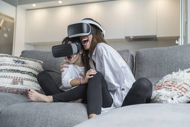 Excited mother and daughter using virtual reality glasses at home - SNF00912