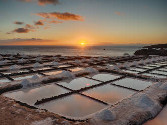 Scenery of salt ponds in shape of squares located on seashore in La Palma on background of orange sunset - ADSF19678