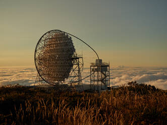 Erstaunlicher Blick auf moderne Teleskope auf einem dunklen Berggipfel gegen Wolken und Sonnenlicht während des Sonnenuntergangs im astronomischen Observatorium auf der Insel La Palma in Spanien - ADSF19684