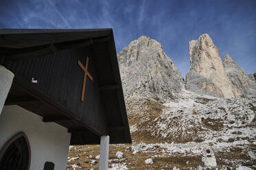 Spektakuläre Kulisse einer kleinen Kirche vor einem rauen Bergkamm bei Tageslicht - ADSF19700