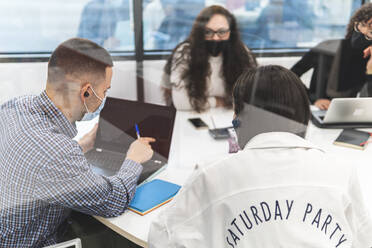 Business people having meeting in board room seen through glass at office during COVID-19 - JAQF00065