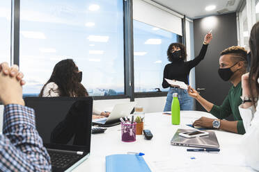 Businesswoman holding diary explaining business strategy to coworkers in meeting at office - JAQF00076