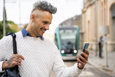 Stilvoller Geschäftsmann mit Smartphone am Bahnhof - AFVF07925