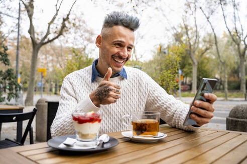 Stilvoller Mann mit Videoanruf über Smartphone im Café - AFVF07942