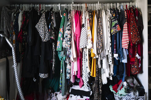 Variation von Damenbekleidung, die auf einem Kleiderständer im Kleiderschrank einer Wohnung hängt - JCMF01757