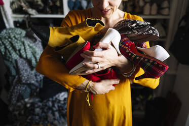 Woman carrying variation of shoes in wardrobe at home - JCMF01761