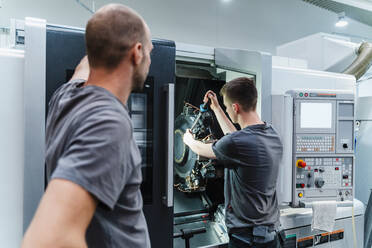 Trainee tightening bolts of machine while standing by instructor at industry - DIGF13740