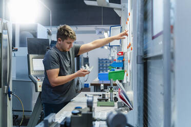 Young engineer pointing toward whiteboard while working at industry - DIGF13766