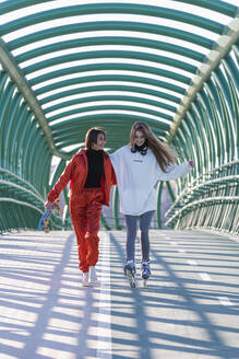 Junge Frau, die mit ihrem Freund auf einer Brücke Schlittschuh läuft - JRVF00032