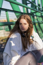 Schönes jugendliches Mädchen sitzt auf einer Brücke - JRVF00040