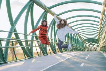 Happy friends enjoying together while jumping on bridge - JRVF00061