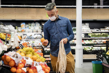 Mann mit Gesichtsmaske kauft Obst im Supermarkt - AFVF07947