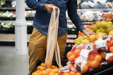 Mittelteil eines Mannes, der im Supermarkt Obst kauft - AFVF07948