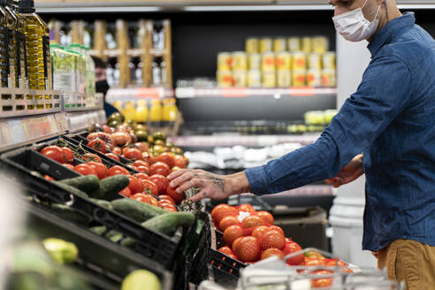 Mittelteil eines Mannes mit Gesichtsmaske beim Kauf von Gemüse im Supermarkt - AFVF07951