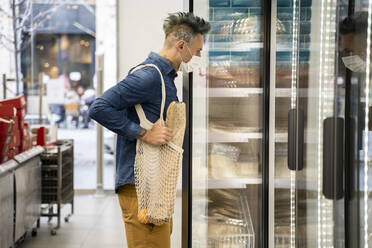 Stilvoller Mann schaut in eine Vitrine im Supermarkt - AFVF07953