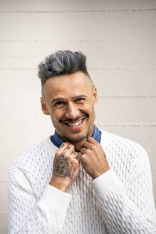Lächelnde stilvolle gut aussehend Mann mit Tattoo gegen weiße Wand - AFVF07982