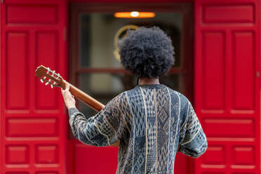 Junger Mann spielt Gitarre, während er vor einem Gebäude steht - OCMF01955