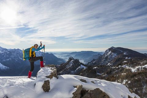 Männlicher Wanderer klettert auf dem Gipfel eines Berges gegen den Himmel, Orobische Alpen, Lecco, Italien, lizenzfreies Stockfoto