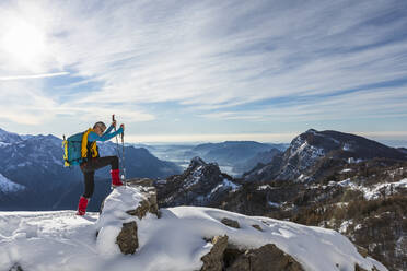 Männlicher Wanderer klettert auf dem Gipfel eines Berges gegen den Himmel, Orobische Alpen, Lecco, Italien - MCVF00693