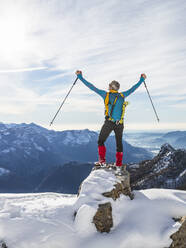 Unbekümmerter männlicher Wanderer mit erhobenen Armen auf einem verschneiten Berg stehend, Orobische Alpen, Lecco, Italien - MCVF00694