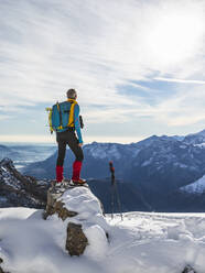 Männlicher Wanderer mit Rucksack, der die Aussicht betrachtet, während er auf dem Gipfel eines Berges steht, Orobische Alpen, Lecco, Italien - MCVF00700