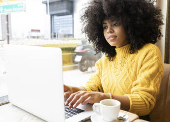 Frau arbeitet am Laptop, während sie in einem Café sitzt - JCCMF00362