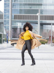 Young woman wearing jacket dancing while standing in city - JCCMF00399