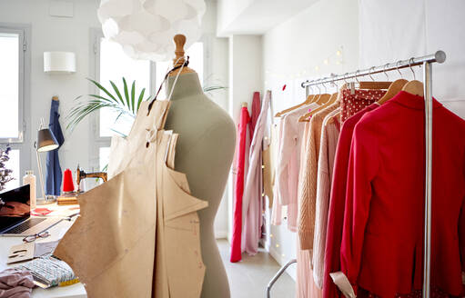 Cardboards hanging on dressmaker's model against clothes rack at design studio - VEGF03404
