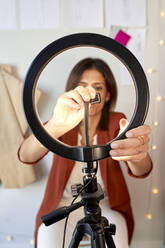 Female fashion designer adjusting circle light for vlogging at atelier - VEGF03457