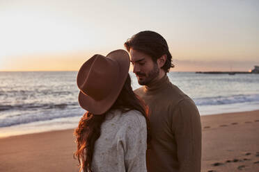 Paar steht bei Sonnenaufgang von Angesicht zu Angesicht am Strand - VEGF03464