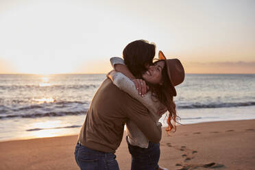 Young couple embracing each other while standing at beach - VEGF03465