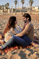 Junges Paar, das am Strand sitzt und eine Romanze hat - VEGF03481