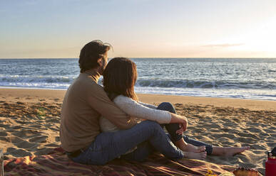 Junges Paar mit Blick auf das Meer am Strand sitzend - VEGF03489