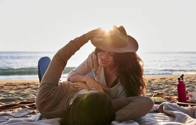 Verspieltes junges Paar ruht sich am Strand aus - VEGF03497