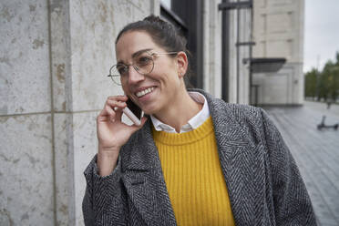 Lächelnde Unternehmerin, die in der Stadt mit einem Mobiltelefon spricht - SDAHF01095