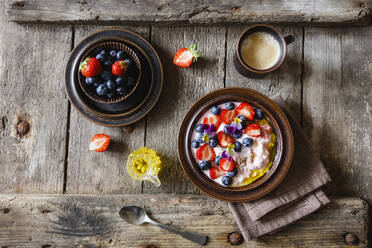 Tasse Kaffee und Quarkteller mit Erdbeeren, Heidelbeeren und essbaren Blüten - EVGF03850