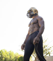 African sportsman looking away while wearing helmet against clear sky - JCCMF00439