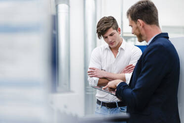 Male professionals discussing with engineer over digital tablet in factory - DIGF13780