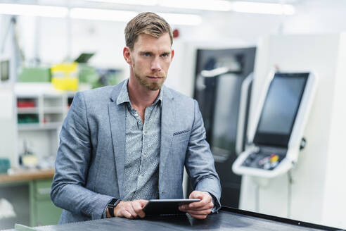 Männlicher Fachmann mit digitalem Tablet, der bei der Arbeit in der Industrie nachdenkt - DIGF13824